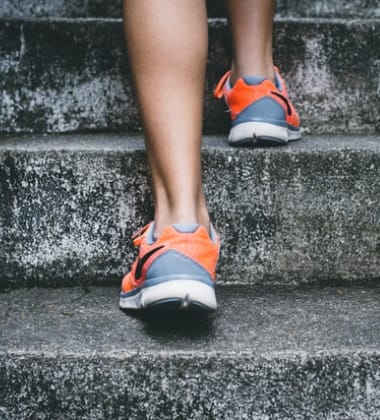 Ein symbolisches Bild für die Pflanze Moringa: eine sportliche Frau steigt mit Energie und leichten Beinen eine Treppe hoch.
